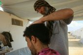 أبو خليل يفتتح في خيمته محلاً للحلاقة بأدوات بسيطة وإرادة قوية