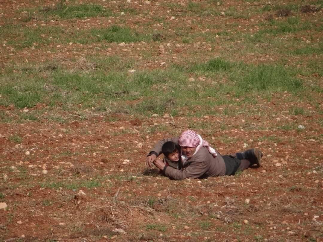 أب يحتضن طفله لحمايته من صاروخ روسي استهدف قوافل النازحين في إدلب