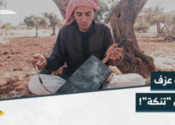 منير شاب يعزف على ربابة صنعها بنفسه بأدوات بسيطة في مكان تهجيره